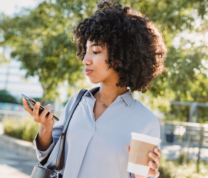 An eccuity member checking her portfolio on her phone, coffee in hand